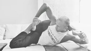 Leg flexibility stretching exercise performed lying on floor mat
