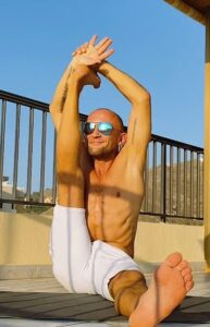 Woman doing overhead stretching exercise outdoors in orange fitness top