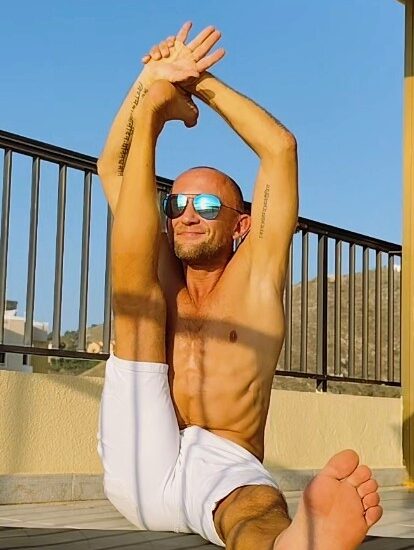 Woman doing overhead stretching exercise outdoors in orange fitness top